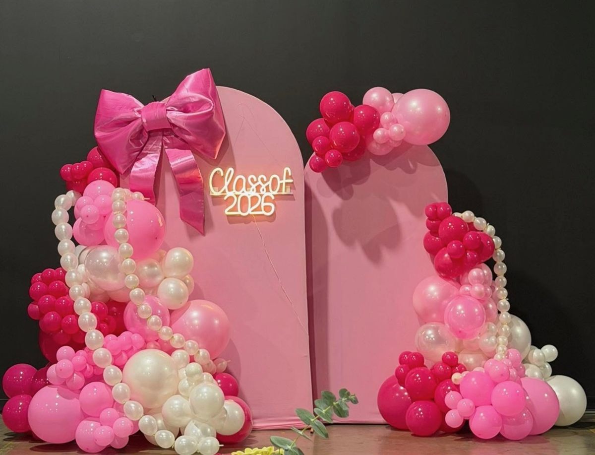 'Class of 2026' graduation backdrop in pinks with a giant satin bow, pearl strands, and balloon garlands