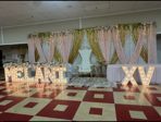 Quinceañera ballroom with 'MELANI XV' marquee letters and pink and gold draping