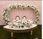 Sweetheart table wrapped in white roses under a floral arch with a pink backdrop