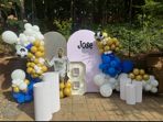 Blue, white, and gold balloon garland around a round birthday backdrop