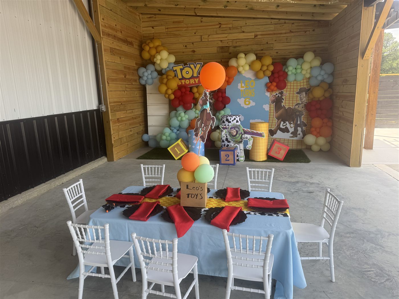 Toy Story 'Leo Turns 6' birthday with balloon garlands, character backdrops, and a styled kids' table with white chiavari chairs